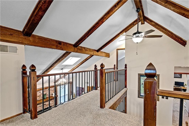 corridor with carpet, visible vents, an inviting chandelier, lofted ceiling with skylight, and an upstairs landing