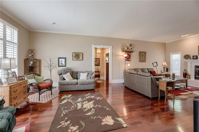 living room with baseboards, dark wood finished floors, crown molding, and a glass covered fireplace