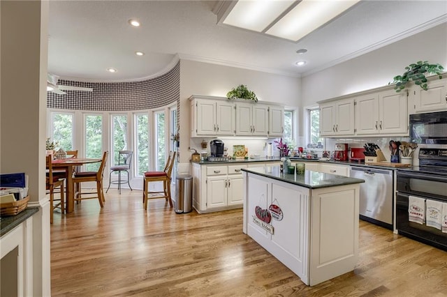 kitchen featuring black appliances, dark countertops, a center island, and white cabinets