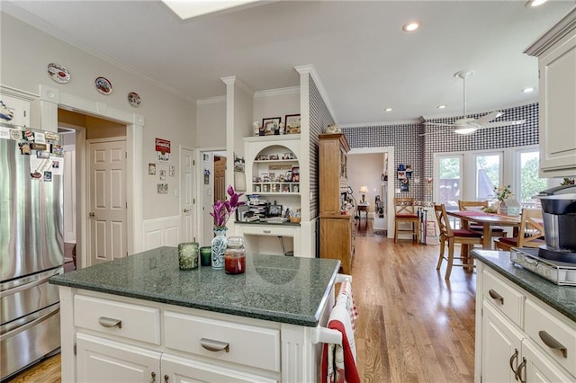 kitchen featuring white cabinets, light wood-style floors, freestanding refrigerator, a center island, and crown molding