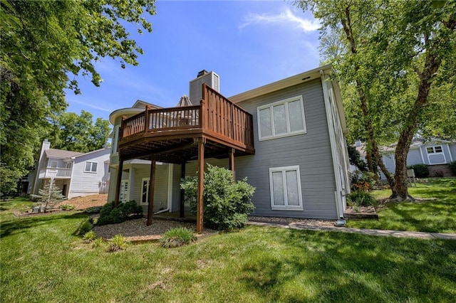 rear view of property featuring a chimney, a lawn, and a deck