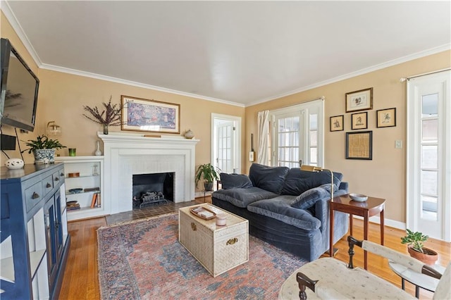 living area featuring wood finished floors, ornamental molding, a brick fireplace, and baseboards