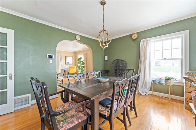 319 S Elm St, Ottawa, KS 66067 - dining room with arched walkways, light wood finished floors, and ornamental molding