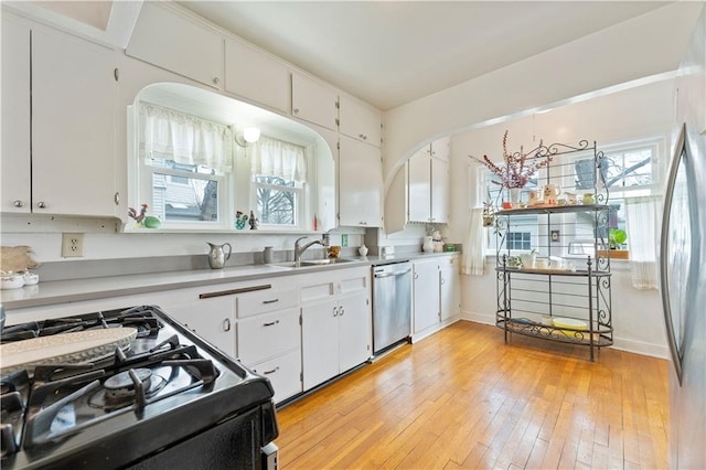 319 S Elm St, Ottawa, KS 66067 - kitchen with stainless steel appliances, light countertops, white cabinetry, light wood finished floors, and arched walkways