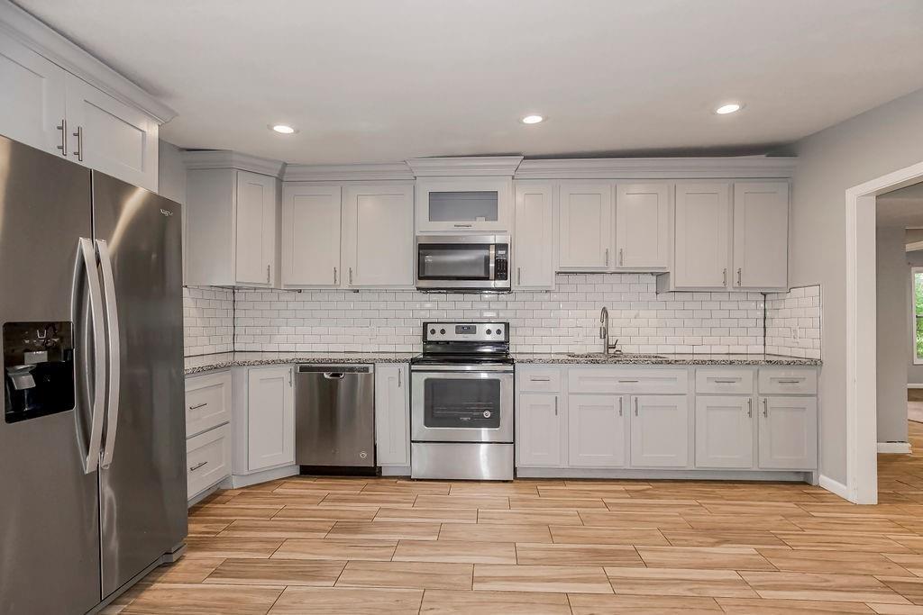 3361 N 60th St, Kansas City, KS 66104 - kitchen with wood tiled floor, tasteful backsplash, appliances with stainless steel finishes, and a sink