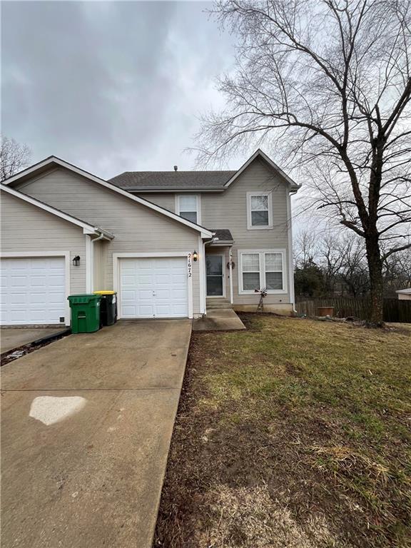 traditional home with concrete driveway, a front lawn, an attached garage, and fence