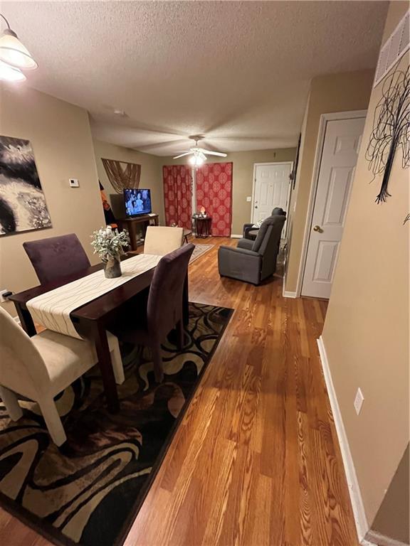 dining room featuring a textured ceiling, wood finished floors, and a ceiling fan