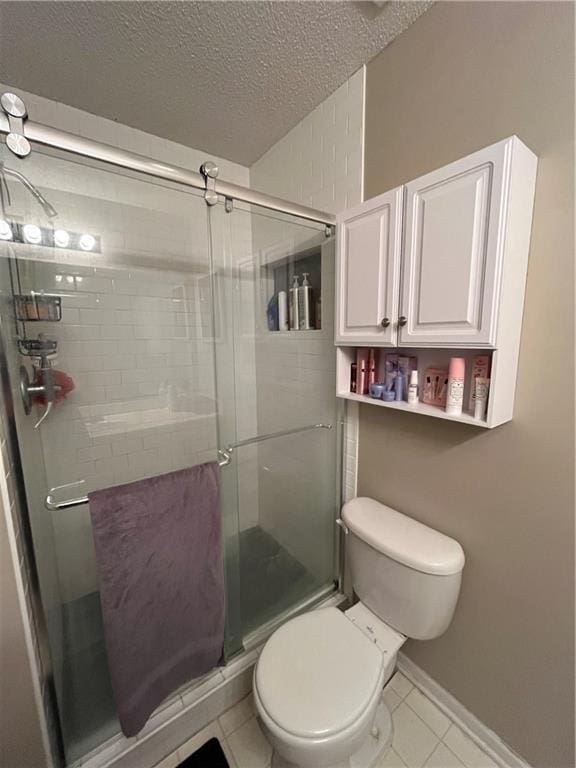 full bathroom featuring a textured ceiling, tile patterned flooring, a shower stall, and toilet