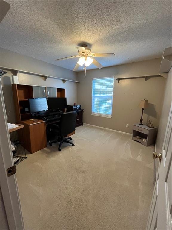 office with baseboards, ceiling fan, a textured ceiling, and light colored carpet