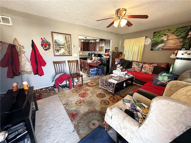 carpeted living room featuring a textured ceiling, visible vents, and a ceiling fan