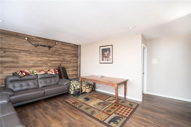 living area featuring baseboards, dark wood-style flooring, a textured ceiling, and wooden walls