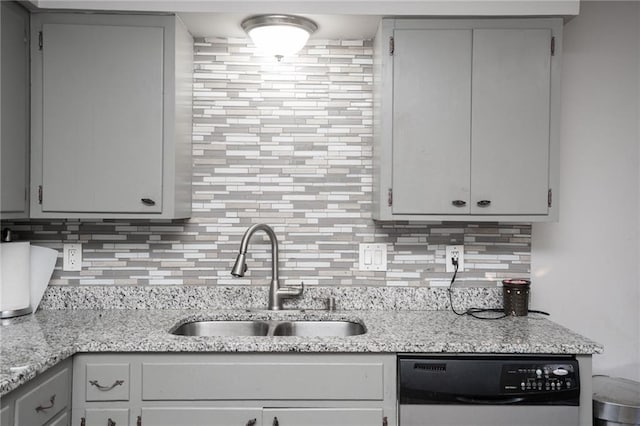 kitchen with a sink, light stone counters, backsplash, and dishwasher