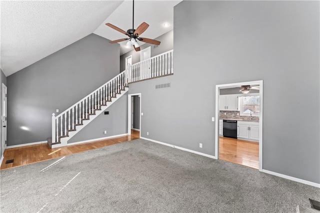 unfurnished living room with a sink, visible vents, baseboards, stairs, and a ceiling fan