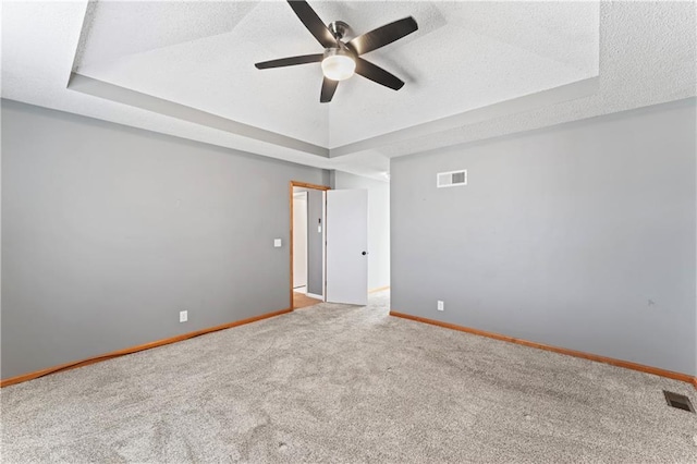 spare room featuring visible vents, a tray ceiling, and baseboards