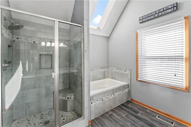 bathroom featuring a stall shower, visible vents, lofted ceiling with skylight, a garden tub, and wood finish floors