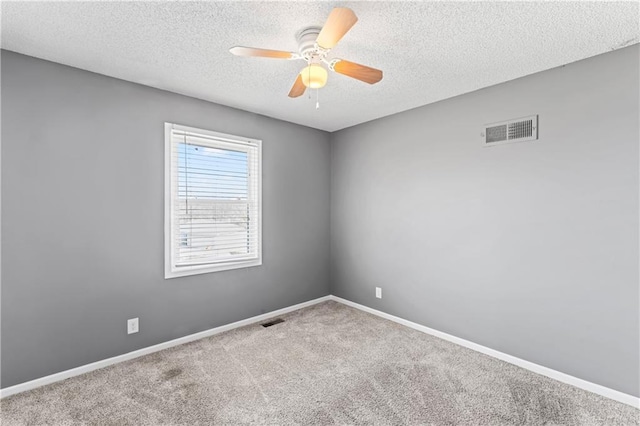 carpeted empty room with a textured ceiling, a ceiling fan, visible vents, and baseboards