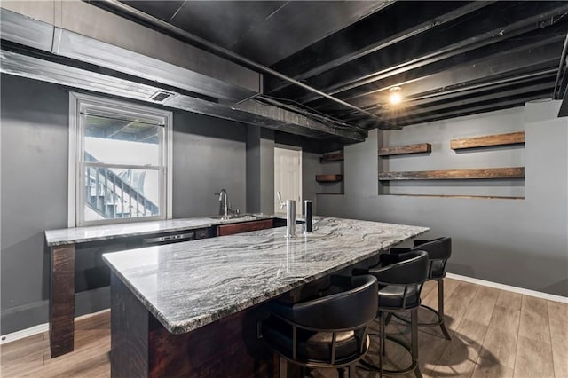 bar featuring light wood-style floors, baseboards, and a sink