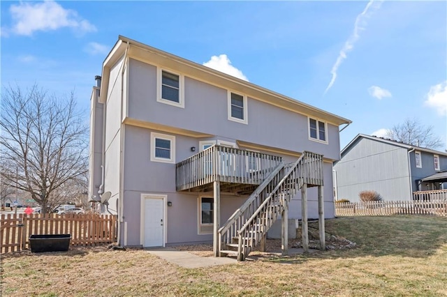 back of property with fence, stairway, a deck, and a lawn