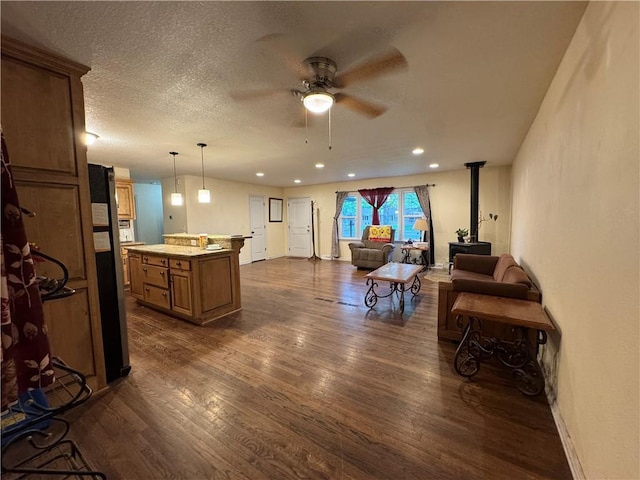 1403 E Mechanic St, Harrisonville, MO 64701 - living room featuring ceiling fan, a wood stove, baseboards, recessed lighting, and dark wood-type flooring