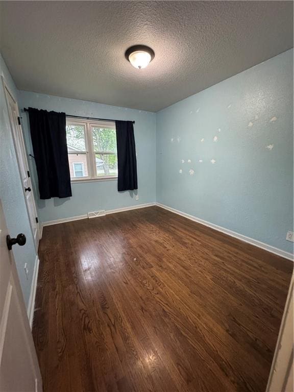 1403 E Mechanic St, Harrisonville, MO 64701 - empty room with baseboards, visible vents, a textured ceiling, and wood finished floors