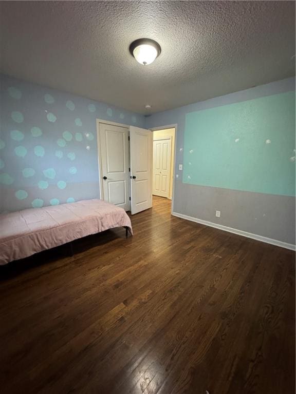 1403 E Mechanic St, Harrisonville, MO 64701 - bedroom with baseboards, wallpapered walls, dark wood-style flooring, and a textured ceiling