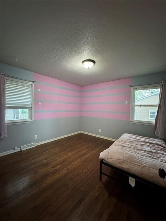 1403 E Mechanic St, Harrisonville, MO 64701 - unfurnished bedroom featuring baseboards, dark wood-style flooring, a textured ceiling, and visible vents