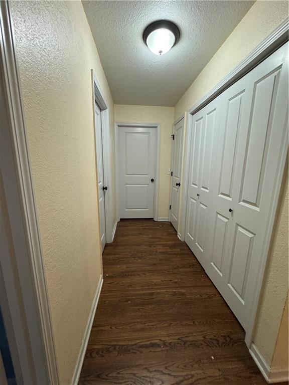 1403 E Mechanic St, Harrisonville, MO 64701 - hall featuring baseboards, a textured wall, dark wood-style flooring, and a textured ceiling