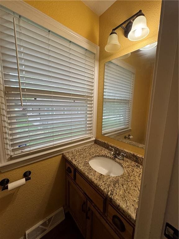 1403 E Mechanic St, Harrisonville, MO 64701 - bathroom with a textured wall, visible vents, plenty of natural light, and vanity