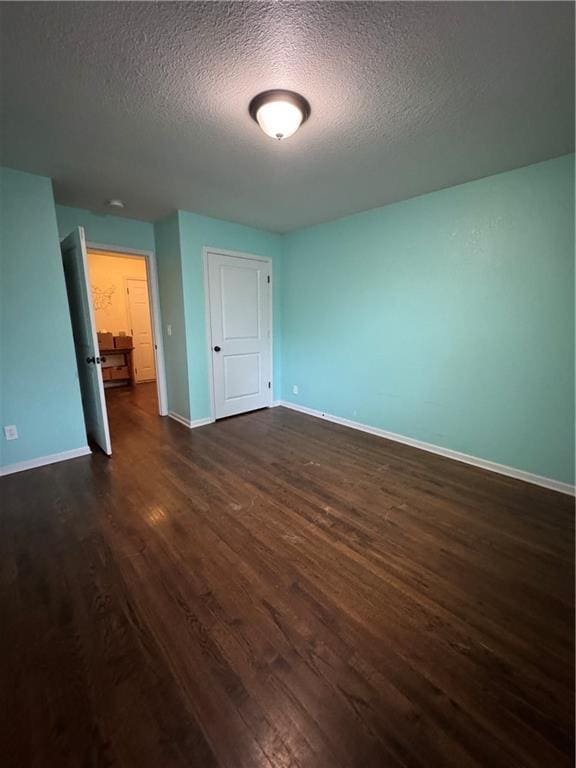 1403 E Mechanic St, Harrisonville, MO 64701 - unfurnished room with baseboards, a textured ceiling, and dark wood-type flooring