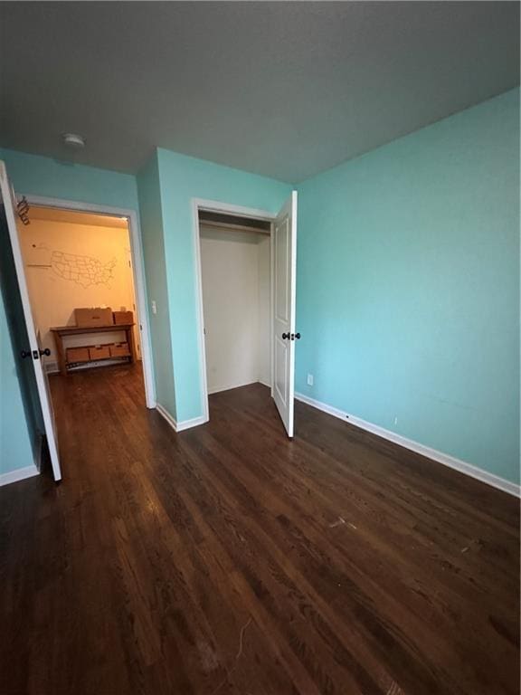 1403 E Mechanic St, Harrisonville, MO 64701 - unfurnished bedroom featuring baseboards, dark wood-style floors, and a closet