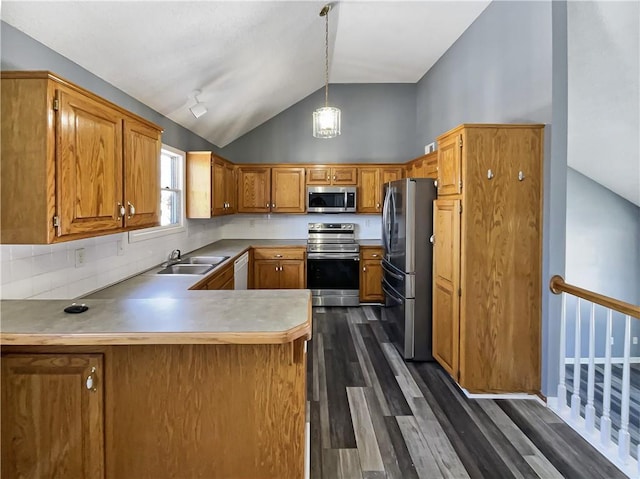 kitchen featuring a peninsula, a sink, hanging light fixtures, appliances with stainless steel finishes, and light countertops