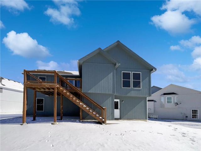 snow covered rear of property featuring stairway and a deck