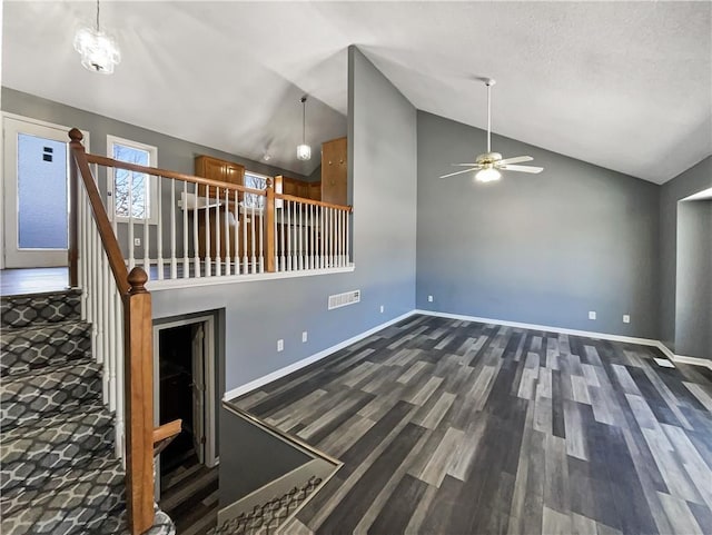 unfurnished living room featuring lofted ceiling, baseboards, visible vents, and dark wood-type flooring