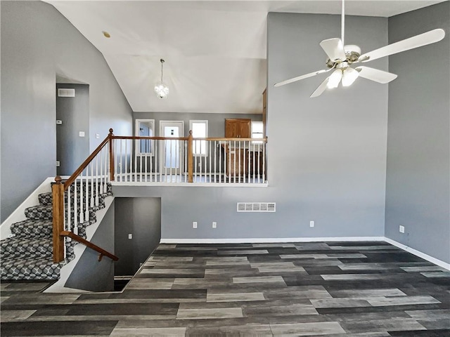 spare room with baseboards, visible vents, dark wood finished floors, high vaulted ceiling, and ceiling fan with notable chandelier