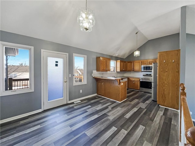 kitchen featuring light countertops, hanging light fixtures, appliances with stainless steel finishes, brown cabinetry, and a peninsula