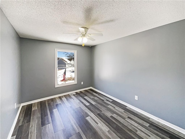 spare room with ceiling fan, a textured ceiling, baseboards, and dark wood-type flooring