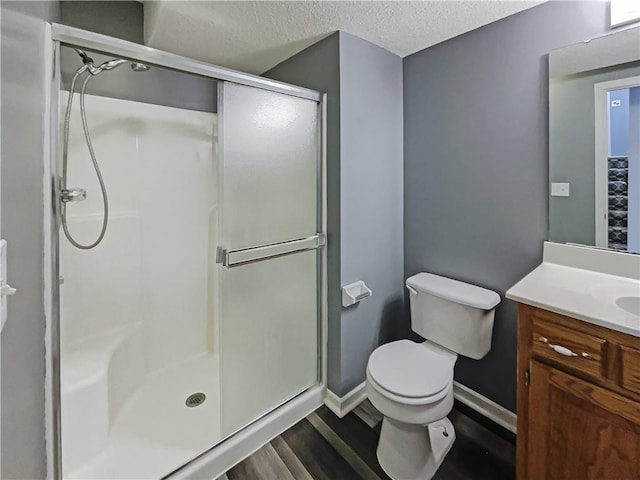 bathroom with toilet, a stall shower, wood finished floors, and vanity