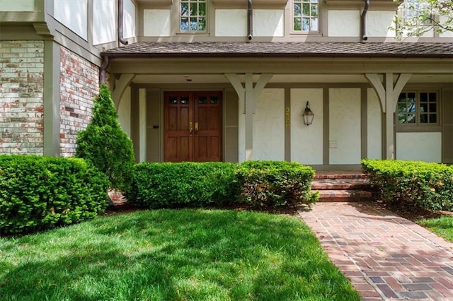 property entrance featuring stucco siding, a yard, and a porch