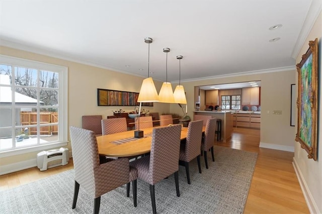 dining area featuring crown molding, baseboards, and light wood finished floors