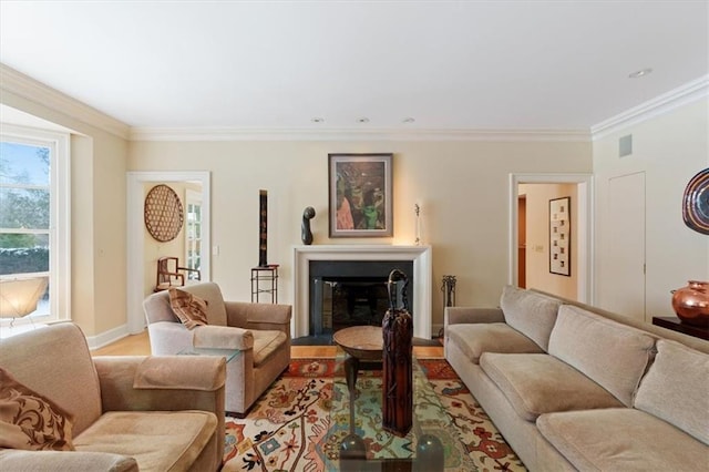 living room featuring light wood-type flooring, baseboards, crown molding, and a glass covered fireplace