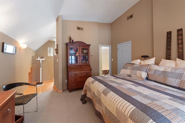 bedroom featuring light carpet, vaulted ceiling, and visible vents