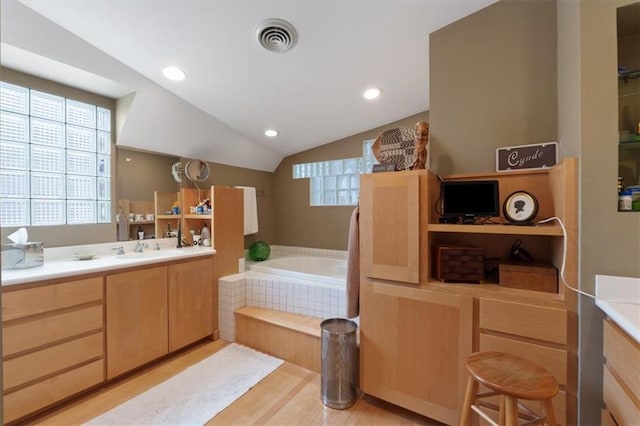 full bathroom featuring vanity, wood finished floors, lofted ceiling, visible vents, and a garden tub