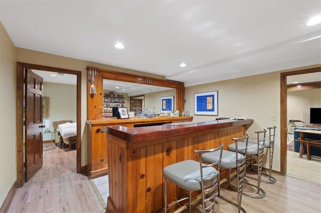 bar featuring light wood-type flooring, a dry bar, and baseboards