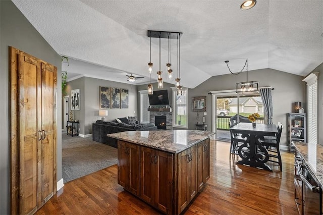 20880 W 224th St, Spring Hill, KS 66083 - kitchen featuring a stone fireplace, a textured ceiling, vaulted ceiling, dark wood-style flooring, and ceiling fan