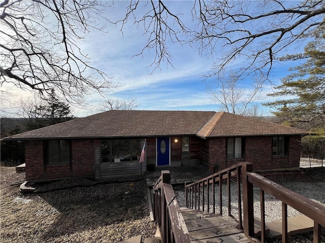 ranch-style house featuring roof with shingles and brick siding