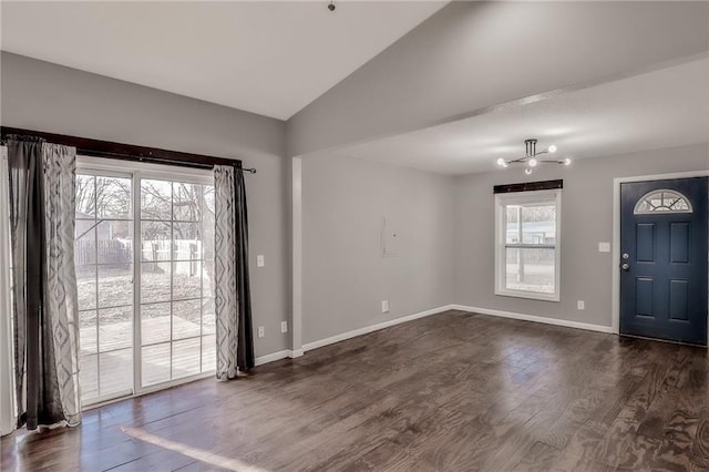 foyer entrance featuring dark wood-type flooring, baseboards, vaulted ceiling, and a wealth of natural light