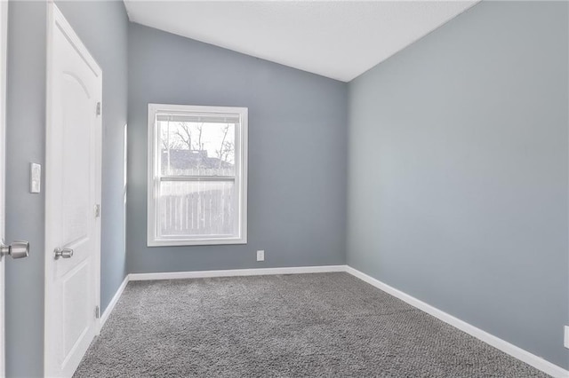 carpeted spare room featuring vaulted ceiling and baseboards