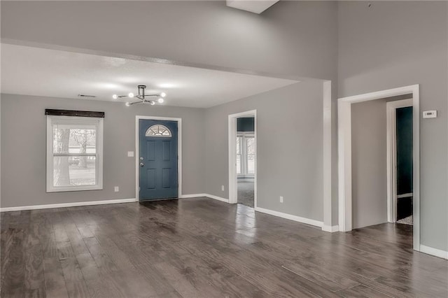 entryway featuring dark wood-style floors, baseboards, visible vents, and an inviting chandelier