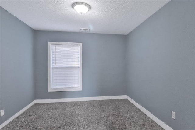 spare room featuring a textured ceiling, carpet floors, visible vents, and baseboards