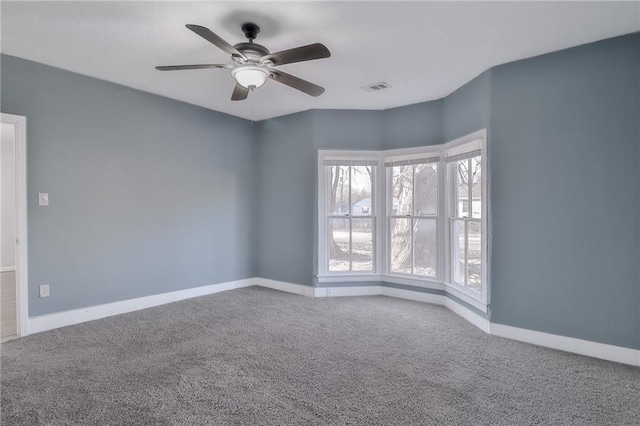 carpeted spare room with ceiling fan, visible vents, and baseboards